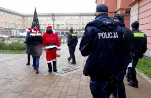 Idą w patrol policjanci, strażnicy miejscy, Mikołaj i kobiety z czerwonymi czapeczkami.