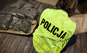 Policjantka w żółtej kamizelce obok ułożone worki z marihuaną.