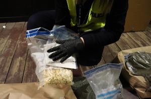 Policjantka trzyma worek z narkotykami, ma założona odblaskową kamizelkę oraz rękawiczki.