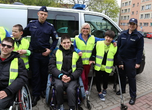 Zdjęcie grupowe, na którym widoczny policjant, policjantka, opiekunowie i osoby na wózku.