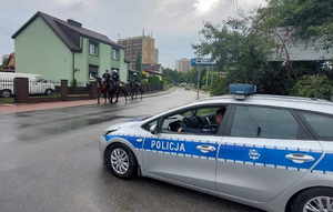 Widoczny radiowóz, dalej policyjni jeżyccy na koniach.