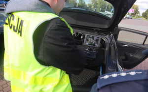 Policjant w kamizelce odblaskowej obsługuje monitor z drona, widoczne pagony umundurowanego policjanta.