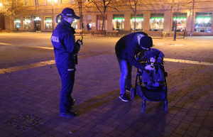 Na zdjęciu umundurowana policjantka oraz meżczyzna i dziecko w wózku. Mężczyzna zakłada odblask na wózek.