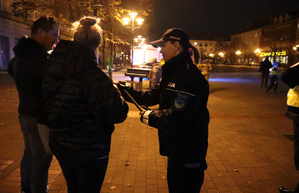 Na zdjęciu umundurowana policjantka oraz kobieta i mężczyzna, którym policjantka wręcza odblaski.