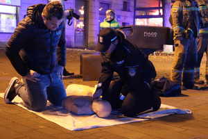 Na zdjęciu umundurowana policjantka i mężczyzna, którzy klęczą przy fantomie do udzielania pierwszej pomocy.