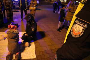 Na zdjęciu umundurowana policjantka i dziecko, którzy klęczą przy fantomie do udzielania pierwszej pomocy.