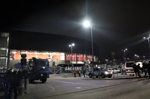 Na zdjęciu policyjne radiowozy oraz armatka wodna oraz umundurowani policjanci biorący udział w zabezpieczeniu meczu. W tle stadion piłkarski.