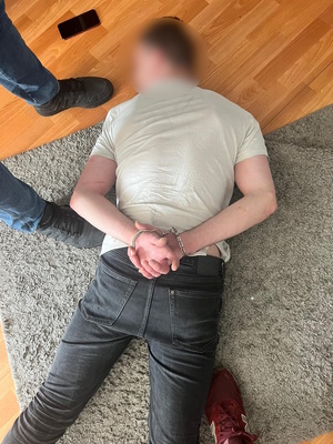 na zdjęciu mężczyzna leżący na podłodze z kajdankami na rękach.