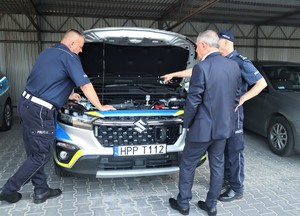 Na zdjęciu radiowóz z otwartą pokrywą silnika, Komendant Miejski Policji w Tychach, policjant Wydziału Ruchu Drogowego w Tychach oraz Prezydent Miasta Tychy.