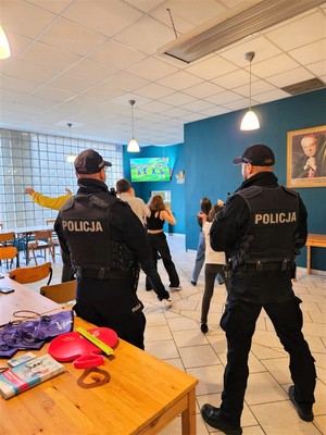 Na zdjęciu umundurowani policjanci podczas spotkania z dziećmi uczestniczącymi w półkolonii.