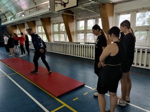 Na zdjęciu instruktor oraz młode osoby na sali gimnastycznej.