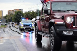 Na zdjęciu radiowóz Policji oraz pojazd z biskupem święcącym pojazdy.