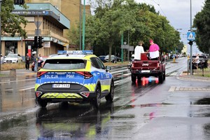 Na zdjęciu radiowóz Policji oraz pojazd z biskupem święcącym pojazdy.