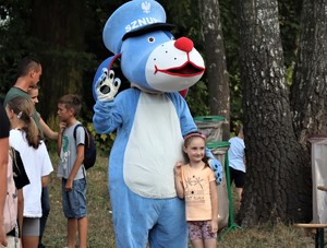 Na zdjęciu maskotka Sznupka z dziewczynką.