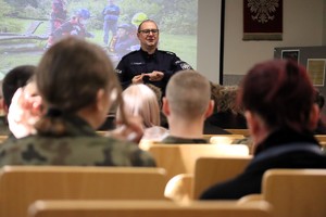 Na zdjęciu umundurowany policjant prowadzący prelekcję dla uczniów.