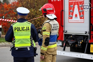 Na zdjęciu umundurowany policjant oraz strażak w kamizelce z napisem o treści Kierujący działaniem ratowniczym.