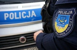 Naszywka na mundurze z napisem Komenda Miejska Policji w Tychach, w tle radiowóz.