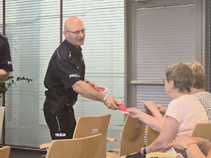 Na zdjęciu policjant rozdający ulotki