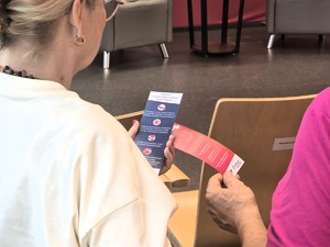 Na zdjęciu seniorzy trzymający ulotki
