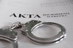 Zdjęcie przedstawiające kajdanki oraz teczkę z napisem akta dochodzenia/śledztwa