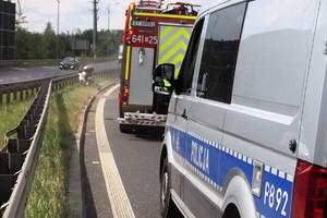 Na zdjęciu radiowóz i wóz straży pożarnej. W tle motocykl