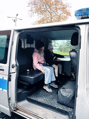 Kolorowe zdjęcie dzieci siedzących w radiowozie.