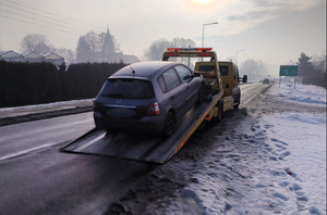 Kolorowe zdjęcie pojazdu marki Honda usuwanego z drogi przy użyciu holownika.