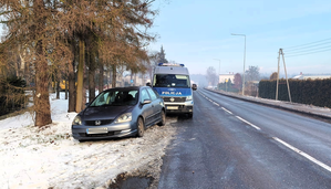 Kolorowe zdjęcie samochodu osobowego marki Honda stojącego na poboczu drogi, obok stoi oznakowany radiowóz Policji.