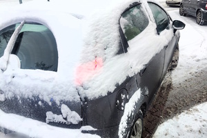 Kolorowe zdjęcie zasypanego śniegiem samochodu.