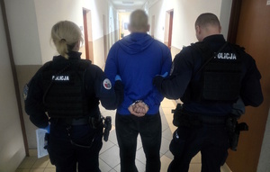 Policjantka i policjant prowadzą zatrzymanego mężczyznę
