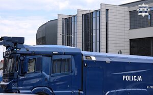 Kolorowe zdjęcie pojazdu specjalnego Policji, tak zwanej "armaty wodnej" na tle budynku stadionu miejskiego w Tychach.