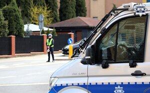 Kolorowe zdjęcie oznakowanego radiowozu Policji, w tle widoczna umundurowana policjantka ruchu drogowego.