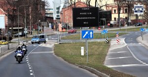 Kolorowe zdjęcie fragmentu drogi, na którym widoczny jest oznakowany radiowóz oraz motocykle policyjne.