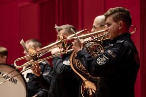 Policjanci orkiestry w mundurach policyjnych stojący z instrumentami na scenie.