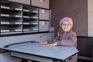 Dziewczynka siedząca w radiowozie przy stoliku.