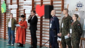 Oficjalne otwarcie eskulapiady. Przemawia dyrektor oraz organizatorka wydarzenia. Widoczni są również stojący obok przemawiających umundurowany policjant oraz kobieta i mężczyzna w mundurach wojskowych.