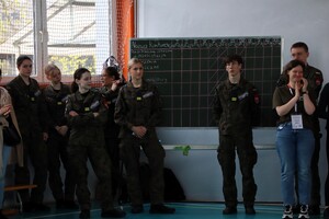 Uczniowie szkoły mundurowej w mundurach wojskowych stojący na tle tablicy kredowej.