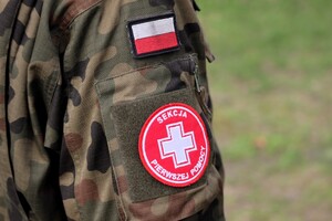 Przedramię umundurowanego w mundur wojskowy ucznia z naszywką sekcji I pomocy.