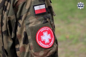 Przedramię umundurowanego w mundur wojskowy ucznia z naszywką sekcji I pomocy.