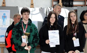 Stojący uczniowie z dyplomami. Za nimi uśmiechnięty Komendant Komendy Miejskiej Policji w Tychach mł. insp. Tomasz Zawadzki