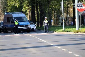 Oznakowany policyjny radiowóz stojący w poprzek drogi, blokując ruch na skrzyżowaniu.
