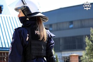policjantka w umundurowaniu oraz kasku ochronnym stojąca na tle stadionu.
