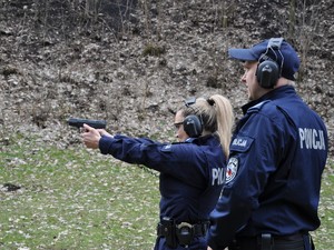 policjantka wykonuje trening strzelecki, obok niej stoi policjant - instruktor