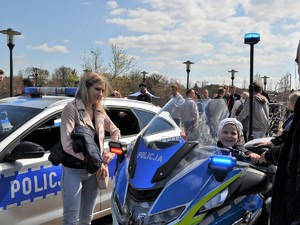 chłopczyk siedzi na policyjnym motocyklu, obok stoi jego mama i policjant