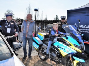 na policyjnym motocyklu siedzi chłopczyk, jego tata rozmawia z policjantami