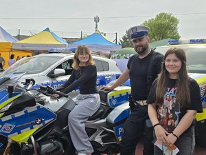 policjant pozuje do zdjęcia z dwiema uczennicami, uczestniczkami Targów edukacyjnych