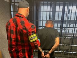 nieumundurowany policjant stoi obok zatrzymanego mężczyzny, stoją tyłem do zdjęcia