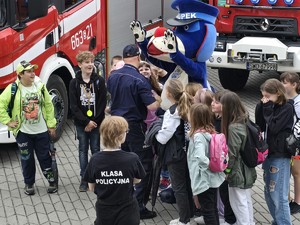 dzieci stoją obok policyjnej maskotki