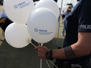 policjant trzyma w ręce balony