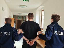 na zdjęciu widać zatrzymanego mężczyznę, który jest prowadzony przez policjantów